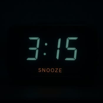 Close-up of an alarm clock snooze bar glowing softly in a dark room