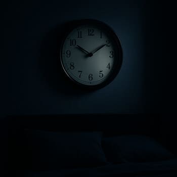 Night bedroom scene with a silent wall clock above a soft headboard